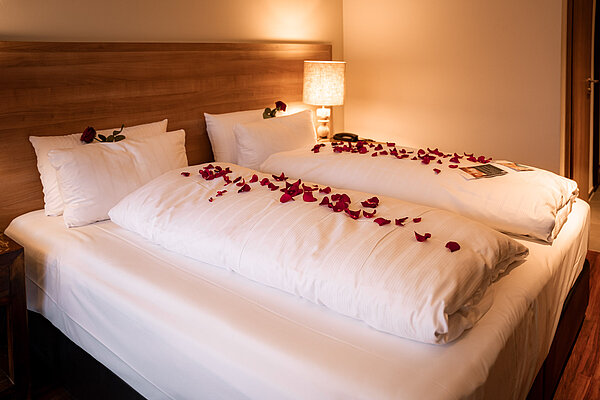Romantisches Zimmer mit Rosenblättern auf dem Bett