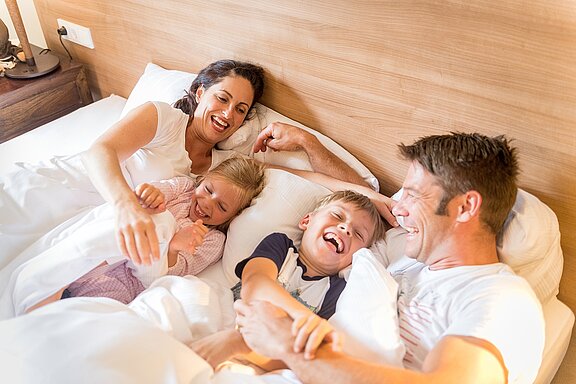 Lachende vierkoepfige Familie im Bett
