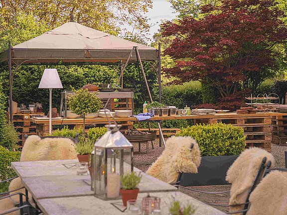 Grillstation und lange Tafel mit Fell auf Stuehlen