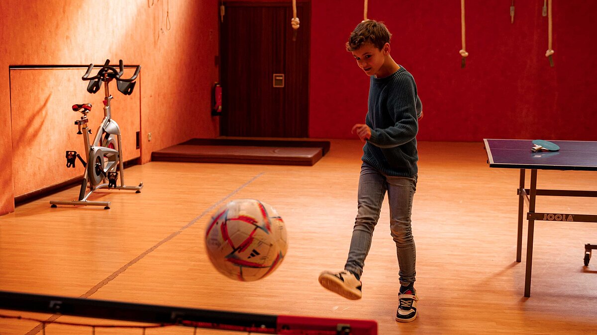 Fussball spielendes Kind in Turnhalle