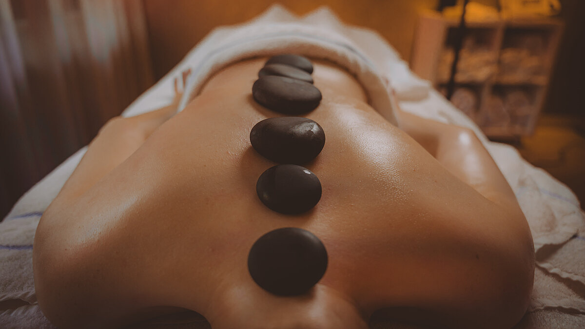 Rueckenmassage mit Massagesteinen