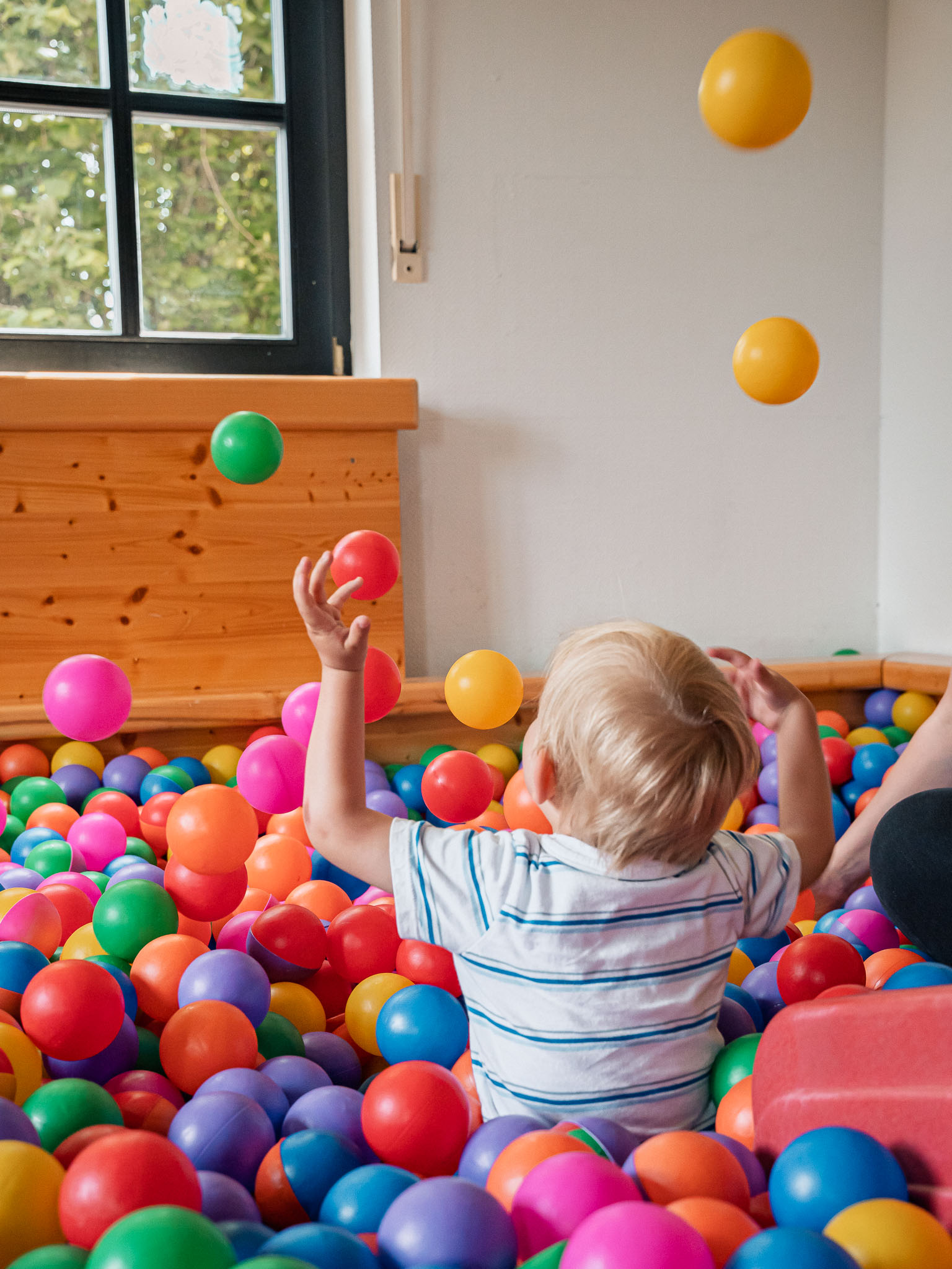 Kind spielt im bunten Bällebad des Marienkäferclubs